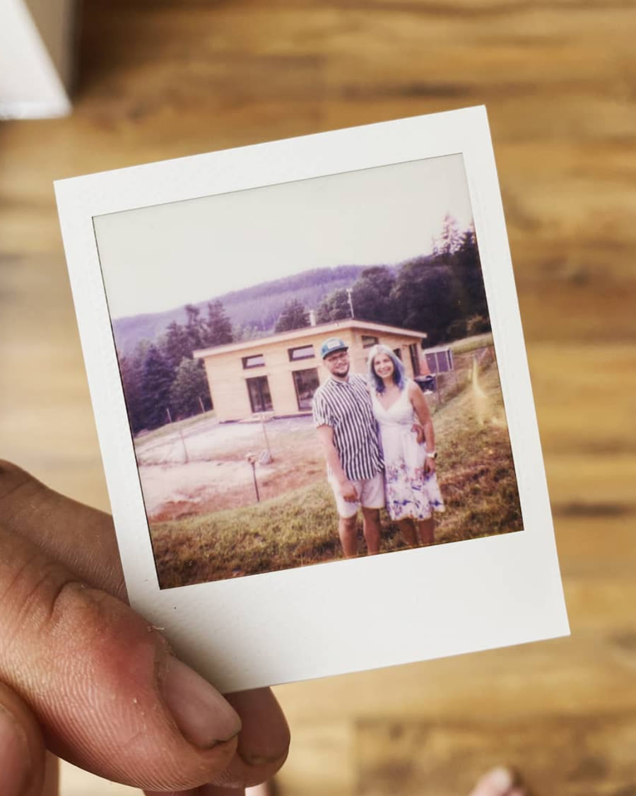 Polaroid: David s manželkou před rozestavěným dřevěným domem